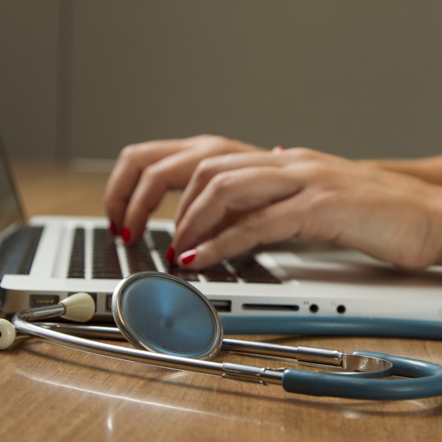 Médica en consultorio utilizando laptop junto a un estetoscopio sobre la mesa